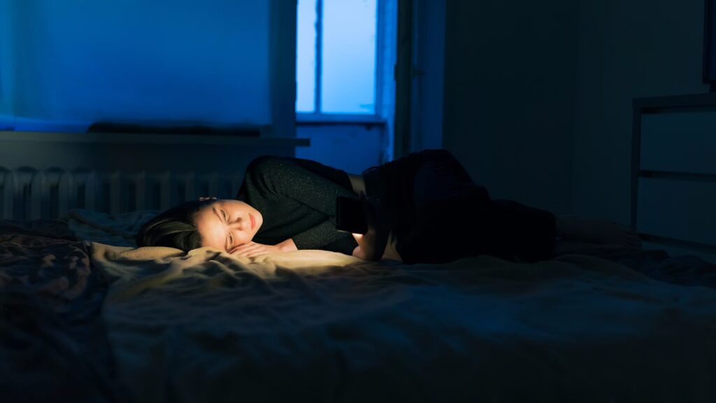 Femme souffrant de réveils nocturnes systématiques à 3h du matin regardant l'horloge avec anxiété
